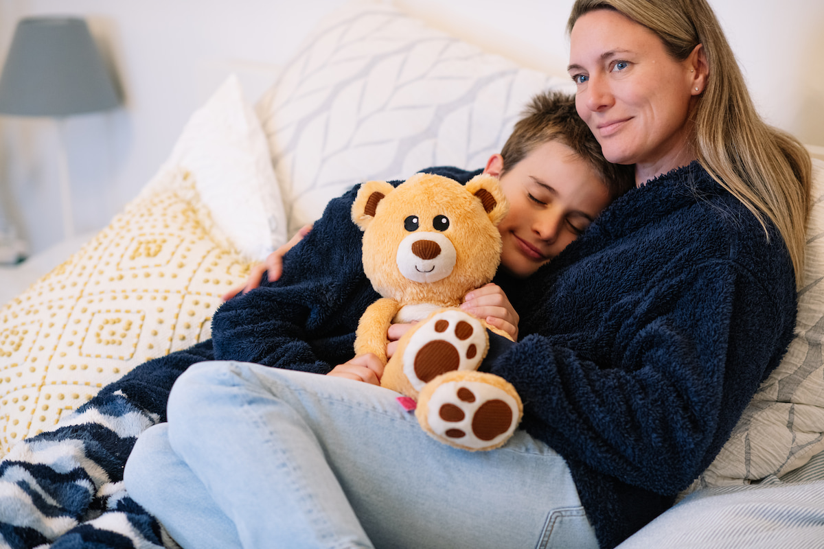Child and mother sitting on a couch holding a Tedology sensory teddy bear