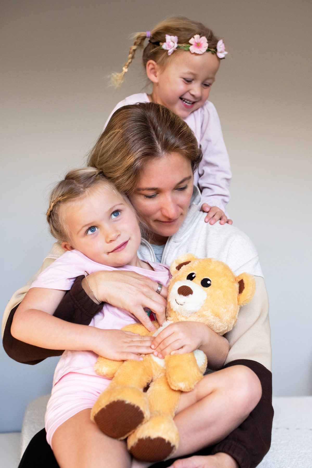 A mum hugging her two children while they hold Teddy the Tedology bear
